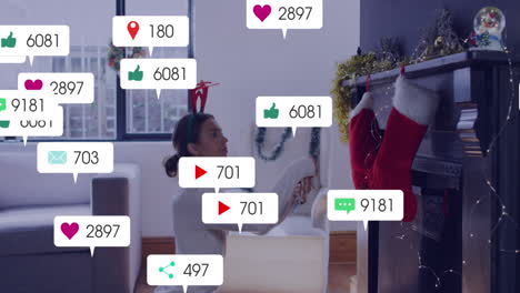 Animation-of-social-media-icons-with-numbers-over-caucasian-woman-decorating-house-for-christmas