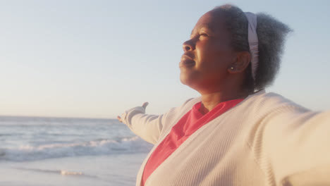 Glückliche-ältere-Afroamerikanische-Frau,-Die-Am-Strand-Die-Arme-Ausbreitet,-In-Zeitlupe