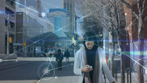 Animation-of-dots-connecting-with-lines-over-young-woman-in-hijab-using-smartphone-on-footpath