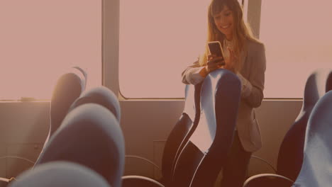 Caucasian-businesswoman-smiling-while-using-smartphone-standing-in-the-bus