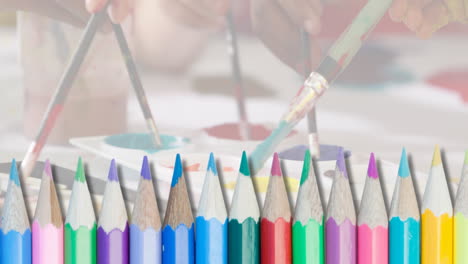 Animation-of-coloured-pencils-over-hands-of-diverse-children-using-brushes-and-paints-in-class