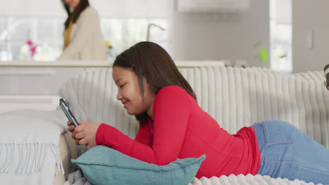 Video-Eines-Glücklichen-Asiatischen-Mädchens,-Das-Mit-Einem-Smartphone-Auf-Dem-Sofa-Entspannt
