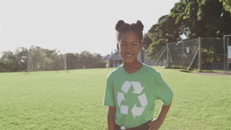 Biracial-girl-stands-proudly-in-a-sunny-outdoor-park-wearing-a-green-recycling-t-shirt