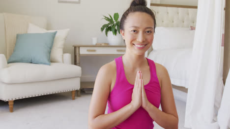 Portrait-of-happy-asian-woman-doing-yoga-and-meditating-in-bedroom,-in-slow-motion