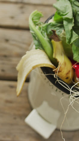 Video-of-white-compost-bin-with-organic-waste-and-copy-space-on-wooden-background