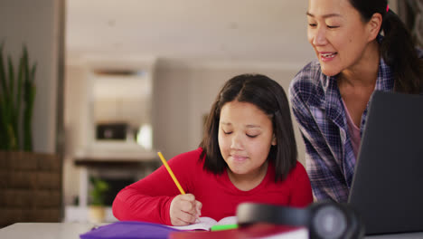 Video-of-happy-asian-mother-and-daughter-doing-homework-together