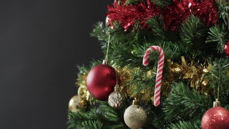 Video-of-christmas-tree-with-candy-cane,-baubles-decorations-and-copy-space-on-black-background