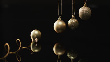 Video-of-gold-christmas-baubles-decorations-with-copy-space-on-black-background