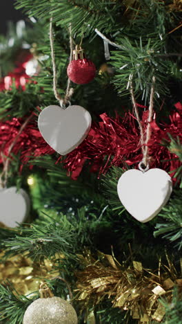 Vertical-video-of-christmas-tree-with-decorations-and-white-hearts-with-copy-space