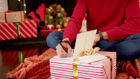 Biracial-man-writing-christmas-greetings-on-christmas-card-at-home,-slow-motion