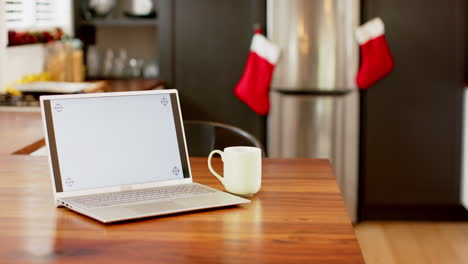 Laptop-with-blank-screen-on-kitchen-countertop-at-christmas,-slow-motion,-copy-space