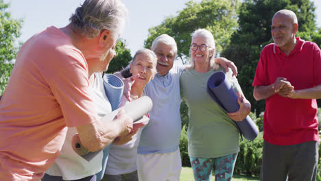 Diverse-group-of-happy-male-and-female-seniors-talking-after-exercising-in-sunny-garden,-slow-motion