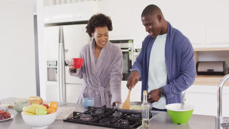 Video-of-happy-african-american-couple-preparing-breakfast-and-coffee-together-in-kitchen