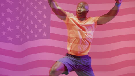 Animation-of-flag-of-america-over-african-american-male-basketball-player-jumping-with-ball