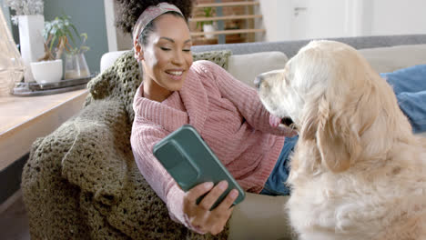 Mujer-Birracial-Feliz-Tomando-Fotos-Con-Un-Perro-Golden-Retriever-Usando-Un-Teléfono-Inteligente-En-Casa,-Cámara-Lenta