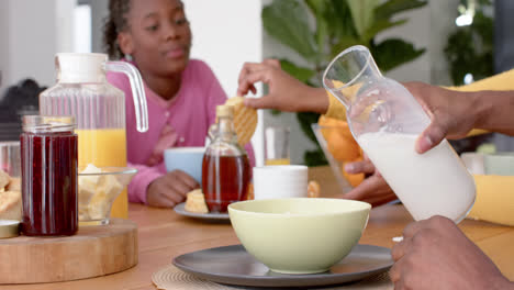Padres-Afroamericanos-Con-Hijo-E-Hija-Desayunando-En-La-Mesa-De-La-Cocina,-Cámara-Lenta