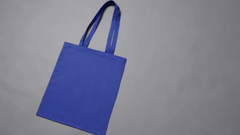 Nahaufnahme-Einer-Blauen-Tasche-Auf-Grauem-Hintergrund,-Mit-Kopierraum,-Zeitlupe