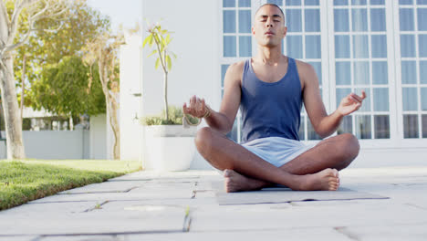 Hombre-Birracial-Enfocado-Practicando-Meditación-De-Yoga-En-Un-Jardín-Soleado,-Cámara-Lenta