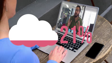 Animation-of-cloud-upload-icon-against-rear-view-of-woman-having-a-video-call-on-laptop-at-a-cafe