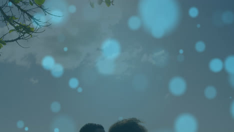 Animation-of-light-spots-over-biracial-couple-kissing