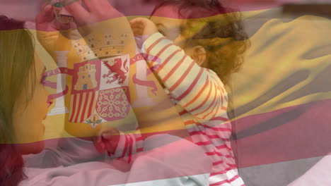 Composite-Video-Einer-Wehenden-Spanischen-Flagge-Vor-Einer-Kaukasischen-Mutter,-Die-Zu-Hause-Mit-Ihrem-Baby-Spielt