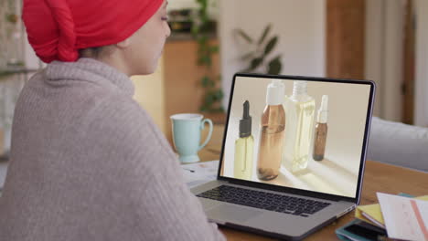 Biracial-woman-at-table-using-laptop,-online-shopping-for-beauty-products,-slow-motion