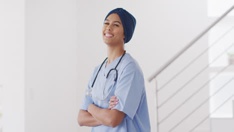 Video-of-happy-biracial-female-doctor-in-hijab-looking-at-camera