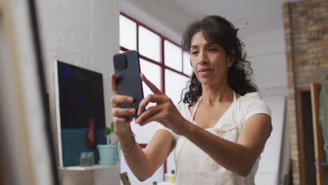 Biracial-woman-texts-on-her-phone-at-home,-with-copy-space