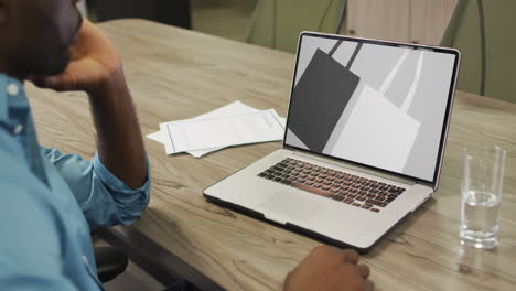 Afroamerikanischer-Mann-Mit-Laptop-Am-Tisch,-Online-Shopping-Für-Taschen,-Zeitlupe