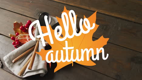 Animation-of-hello-autumn-text-over-cutlery-and-autumn-leaves-over-wooden-background