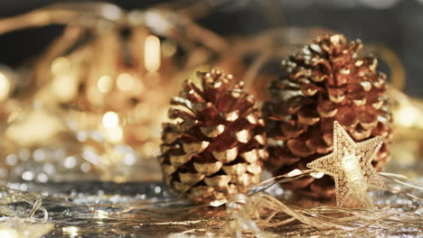 Video-of-christmas-decorations,-pine-cones-and-copy-space-on-fairy-lights-background