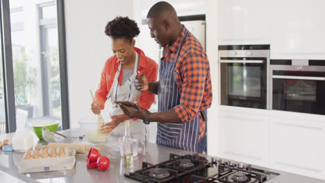 Video-of-happy-african-american-couple-baking-together-with-tablet