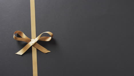 Video-of-gold-gift-ribbon-and-bow-with-copy-space-on-black-background