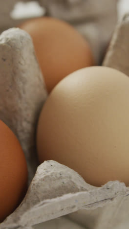Video-of-close-up-of-brown-eggs-in-egg-carton-on-rustic-background