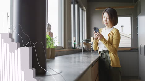 Animation-of-statistical-data-processing-against-asian-woman-using-smartphone-in-the-kitchen-at-home