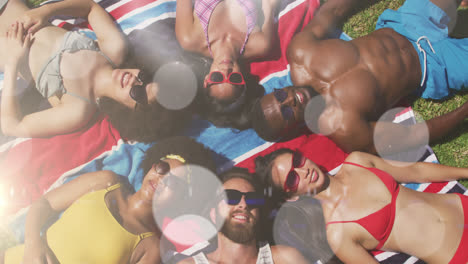 Animation-of-spots-of-light-over-diverse-friends-wearing-sunglasses-lying-on-glass-on-holiday