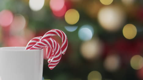 Video-of-white-mug-with-christmas-cnady-canes-and-christmas-tree-lights-with-copy-space
