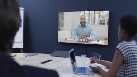 Diverse-business-people-on-video-call-with-african-american-male-colleague-on-screen