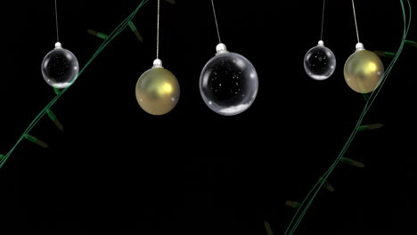 Yellow-christmas-string-lights-flashing-over-swinging-gold-and-clear-baubles-on-black-background