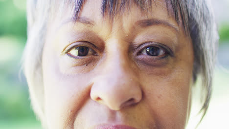 Portrait-close-up-of-eyes-of-senior-biracial-woman-blinking-in-garden,-in-slow-motion