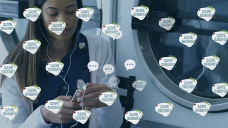 Animation-of-save-energy-text-with-speech-bubble-and-tree-icons-over-biracial-woman-doing-laundry