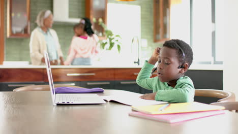 African-american-boy-having-online-class-using-headphones-and-laptop-with-copy-space,-slow-motion