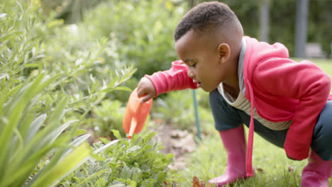 Niño-Afroamericano-Regando-Plantas-En-Un-Jardín-Soleado-En-Cámara-Lenta