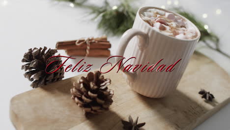 Feliz-navidad-text-in-red-over-pine-cones,-cinnamon-and-christmas-hot-chocolate-with-marshmallows