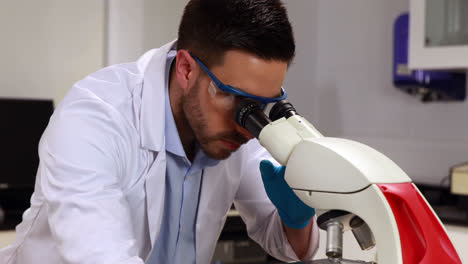 Young-scientist-looking-through-microscope-in-the-lab