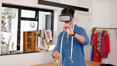 Biracial-male-fashion-designer-using-virtual-reality-headset-in-studio,-slow-motion