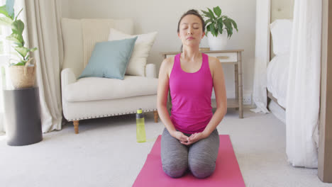 Happy-asian-woman-doing-yoga-and-meditating-in-bedroom,-in-slow-motion