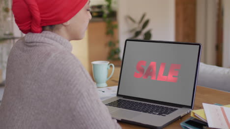 Biracial-Frau-Am-Tisch-Mit-Laptop,-Online-Shopping-Während-Des-Verkaufs,-Zeitlupe