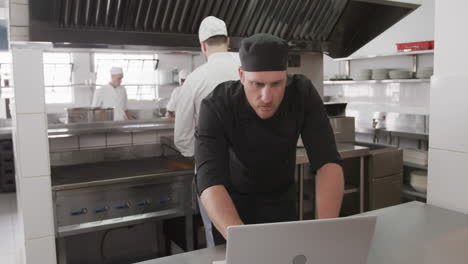 Caucasian-male-chef-using-laptop-in-kitchen,-slow-motion