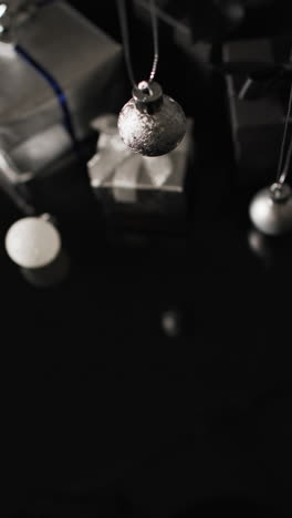 Vertical-video-of-silver-baubles-christmas-decorations-and-copy-space-on-black-background